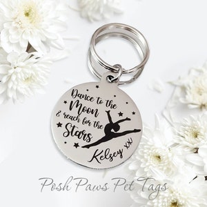 May include: Silver round pet tag with a black silhouette of a gymnast and the text "Dance to the Moon & reach for the Stars" with the name "Kelsey XX" below.