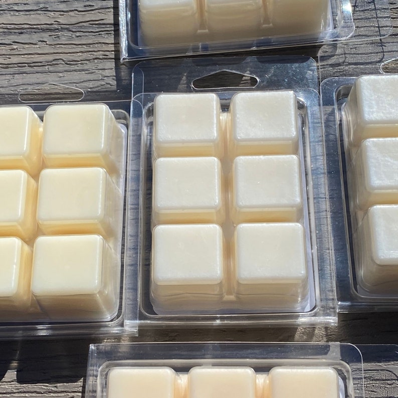 May include: Six clear plastic containers with six individual wax melts in each. The wax melts are white and have a slight shimmer.