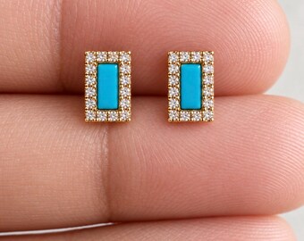 May include: A pair of rectangular stud earrings featuring a central bright turquoise stone surrounded by a border of small clear white crystals set in a gold-toned metal frame. The earrings have a geometric shape and a polished metallic finish.