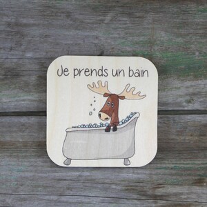 Peut inclure: Une pancarte en bois avec un dessin animé d'un élan prenant un bain dans une baignoire avec des bulles. La pancarte dit "Je prends un bain".