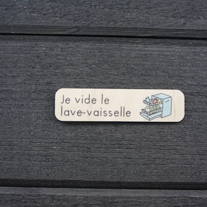 May include: A wooden sign with the text "Je vide le lave-vaisselle" and a cartoon illustration of a dishwasher with dishes inside.