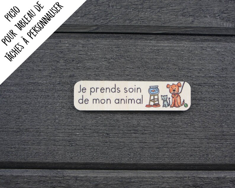 K&ouml;nnte beinhalten: Ein rechteckiges Holzschild mit dem Text "Je prends soin de mon animal" in schwarzer Schrift. Das Schild zeigt eine Comic-Illustration eines Hundes, einer Katze und einer Fischschale.