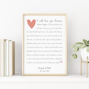 Peut inclure: Un cadre doré contenant une impression avec un poème romantique et un cœur rose. Le texte dit "I will love you forever" et inclut les noms "Amanda & Matt" et la date "16th June 2021".