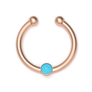 May include: A rose gold-toned circular hoop ring featuring a smooth, polished finish and two small spherical end caps. A single, round, bright turquoise-colored stone is set securely at the base of the hoop, centered directly opposite the opening.