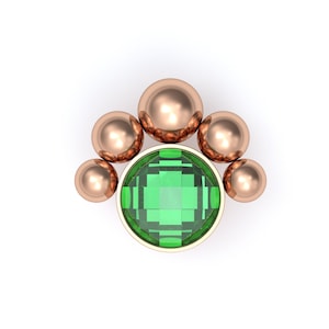 May include: A rose gold body jewelry piece featuring a central round faceted green gemstone set in a bezel. The setting is accented by five smooth, polished rose gold spheres arranged in a fan-like arc above the circular green stone.