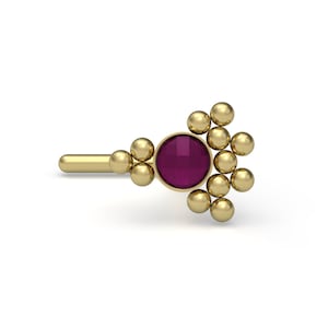 May include: A gold nose ring with a cluster of small gold beads and a single round, dark purple gemstone in the center.