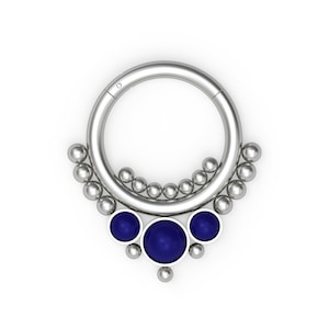 May include: Silver body jewellery with a circular hoop and a dangling cluster of silver beads and three blue gemstones.