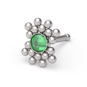 May include: A silver-toned nose stud featuring a central round faceted green gemstone surrounded by a cluster of small polished silver spheres arranged in a sunburst pattern, with a straight post extending from the back of the decorative head.