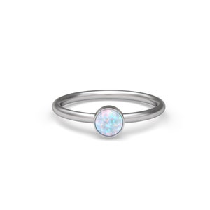 Könnte beinhalten: Ein silberner Ring mit einem runden Opal-Edelstein. Der Opal ist hellblau mit rosafarbenen Nuancen.