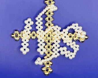 Könnte beinhalten: Ein weißer und goldener Weihnachtsbaumschmuck in Form einer Schneeflocke. Der Schmuck ist aus kleinen, runden Perlen gefertigt und hat eine Schlaufe oben zum Aufhängen.