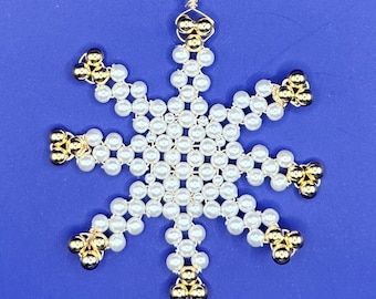 Könnte beinhalten: Ein weißer und goldener Perlen-Schneeflocken-Anhänger mit einer Drahtschlaufe zum Aufhängen.