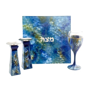May include: A blue and gold Shabbat set with a Kiddush cup, two candlesticks, and a challah board. The challah board features a watercolor-style design with the Hebrew word "Shabbat" written in silver.