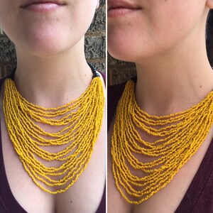 May include: A yellow beaded necklace with multiple strands. The necklace is layered and has a cascading effect. The beads are small and uniform in size.