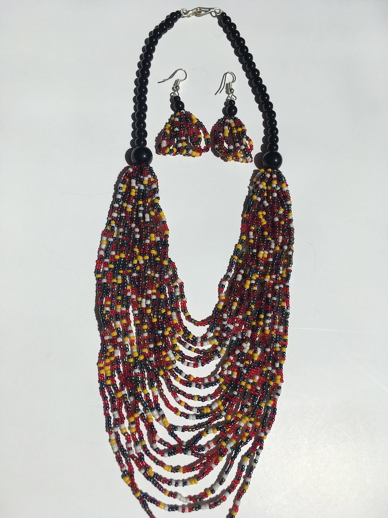 May include: A multi-strand beaded necklace with red, yellow, white, and black beads. The necklace is paired with matching earrings with black beads and silver hooks.