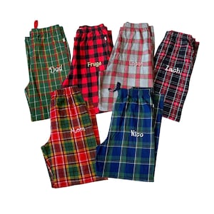 May include: Six pairs of plaid pajama pants with personalized names embroidered on each pair. The names are "Dad", "Fudge", "Logan", "Zach", "Mom", and "Nico".