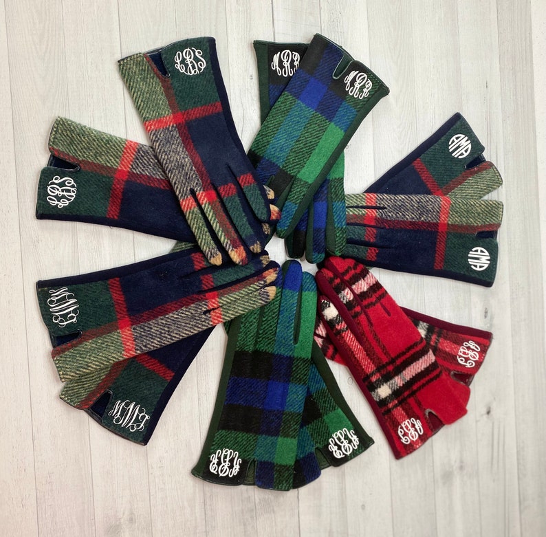 Pu&ograve; includere: Otto paia di guanti in pile a quadri con iniziali ricamate. I guanti sono di vari colori, tra cui rosso, verde, blu e nero.