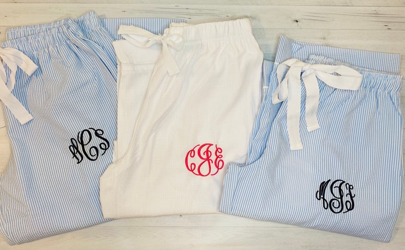 K&ouml;nnte beinhalten: Drei Paar blaue und wei&szlig;e gestreifte Schlafhosen mit verschiedenen monogrammierten Initialen. Die Initialen sind in schwarzem und rotem Faden gestickt.
