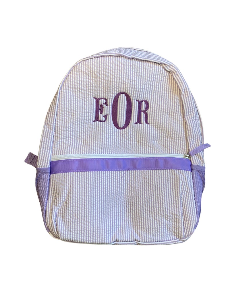 May include: A purple and white striped backpack with a purple zipper and a purple embroidered monogram "EOR".