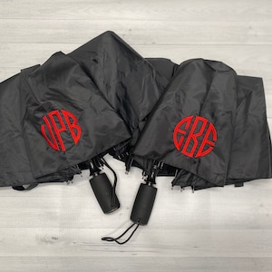 May include: Three black umbrellas with red monogrammed initials. The initials are "J.P.B." and "E.R.E."