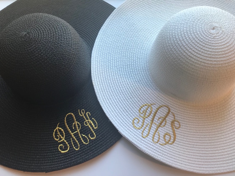 K&ouml;nnte beinhalten: Zwei Sonnenh&uuml;te, einer schwarz und einer wei&szlig;, mit goldenen Stickinitialen. Der schwarze Hut hat die Initialen "J.F.S." und der wei&szlig;e Hut hat die Initialen "R.F.S."