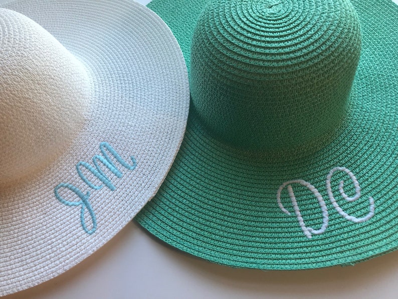 K&ouml;nnte beinhalten: Zwei Strohh&uuml;te, einer wei&szlig; mit blauer Stickerei, die "Jan" sagt, und einer gr&uuml;n mit wei&szlig;er Stickerei, die "De" sagt.