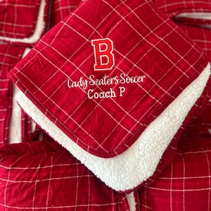 May include: Red and white plaid fleece blanket with a white embroidered letter "B", the words "Lady Seaters Soccer" and "Coach P".