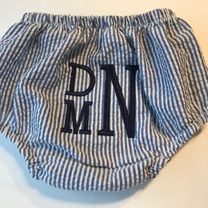 May include: Blue and white striped baby bloomers with a navy blue embroidered monogram "DMN".