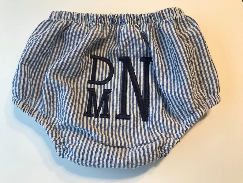 May include: Blue and white striped baby bloomers with a navy blue embroidered monogram "DMN".