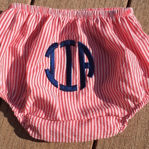 May include: Red and white striped baby bloomers with a blue embroidered monogram "J.J.A."