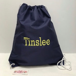 May include: A navy blue drawstring bag with the name "Tinslee" embroidered in yellow.