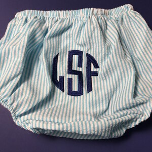 May include: Blue and white striped baby bloomers with a navy blue monogram "LSF" embroidered on the front.