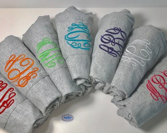 May include: A group of seven gray sweatshirts with different colored embroidered monograms. The monograms are in a script font and are centered on the front of each sweatshirt.