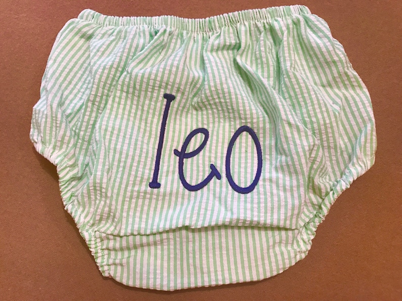 May include: Green and white striped baby bloomers with the name "Leo" embroidered in blue.