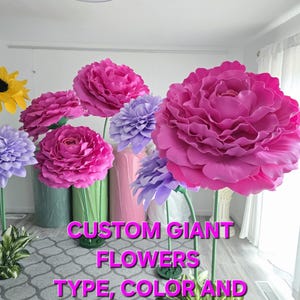 May include: Custom giant flowers in pink, purple and white. The flowers are made of foam and are on stems. The text "CUSTOM GIANT FLOWERS TYPE, COLOR AND SIZE AT YOUR CHOICE" is on the image.
