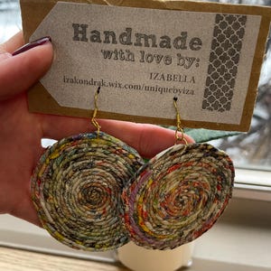 May include: Handmade paper earrings with gold-colored hooks. The earrings are circular, with a spiral design made from colorful recycled paper. The tag reads "Handmade with love by: IZABELLA izakondrak.wix.com/uniquebyiza".