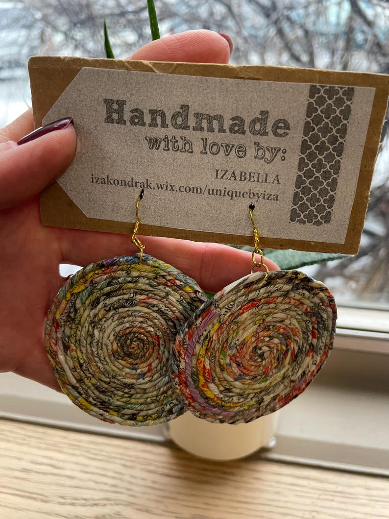 May include: Handmade paper earrings with gold-colored hooks. The earrings are circular, with a spiral design made from colorful recycled paper. The tag reads "Handmade with love by: IZABELLA izakondrak.wix.com/uniquebyiza".