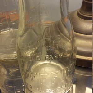 May include: A clear glass milk bottle with the text "Sheffield Farms" and "4% U.S. Fat" embossed on the side.