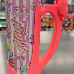 May include: A pink energy drink can with a matching pink handle. The can features a cotton candy design with the words "Cotton Candy" and "Energy". The handle has a bow detail at the top.