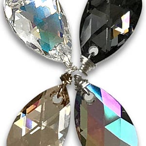 May include: Four teardrop-shaped crystal pendants arranged in a flower-like pattern. Each pendant has a different color: clear, black, brown, and iridescent. The crystals are faceted, reflecting light. Silver-colored metal findings connect the crystals.