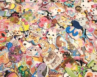 Puede incluir: Un surtido colorido de pegatinas con varios diseños, incluyendo animales, comida y texto. Las pegatinas son de varias formas y tamaños, con acabados brillantes y mate. La paleta de colores es brillante y alegre, con rosas, azules y amarillos.