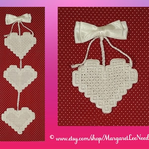 May include: Three white crocheted hearts hanging from a white satin bow on a red background with white polka dots. The hearts are connected by white string.