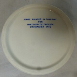 May include: White ceramic bowl with blue text that reads "Hand painted in Thailand for Whittard of Chelsea Dishwasher Safe".