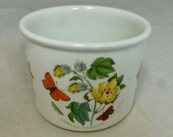 May include: White ceramic cup with a floral design featuring a yellow flower, green leaves, and a butterfly. The text "GOSSYPIUM BARBADENSE" is printed on the bottom of the cup.