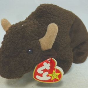 May include: Brown plush bison beanie baby with a tan nose and a red and white Ty tag that says "Ty" and "Beanie Babies".