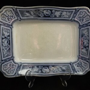 May include: A white rectangular serving platter with a blue and white floral design border. The border features a repeating pattern of flowers, leaves, and scrolls.