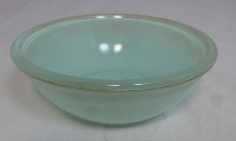 May include: A light blue glass mixing bowl with a slightly raised rim.