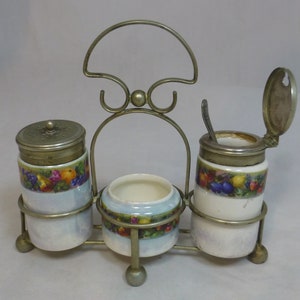 May include: A silver metal stand with three porcelain jars with lids. The jars have a blue and white background with a colorful fruit design. The stand has a handle on top.