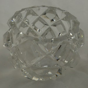 May include: A clear glass salt cellar with a geometric pattern. The cellar is made of cut glass and has a round shape.