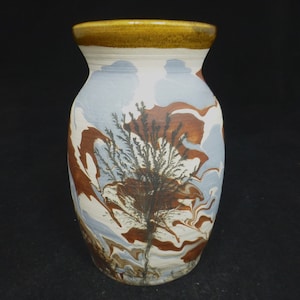 May include: A ceramic vase with a marbled design in shades of brown, white, and blue. The vase has a tree-like pattern in the center.