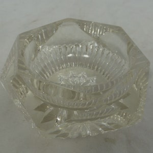 May include: A clear glass salt cellar with a faceted octagonal shape and a fluted interior.
